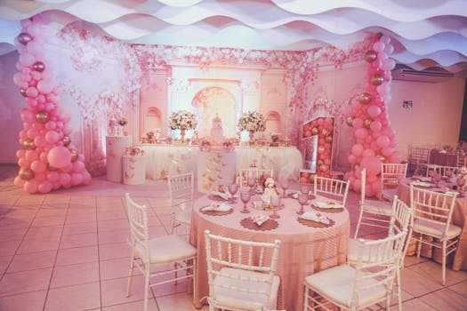 A beautifully decorated pink themed birthday party with floral arrangements and balloon arches.