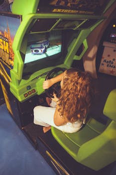 A young girl with curly hair enjoys an arcade racing game, highlighting childhood fun.