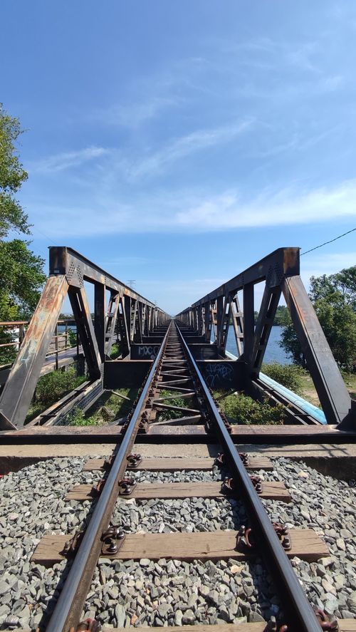 Free Captivating view of a rustic railway bridge extending into the horizon under a clear blue sky. Stock Photo