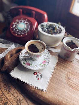 Charming vintage coffee scene with red rotary phone and floral porcelain cup.