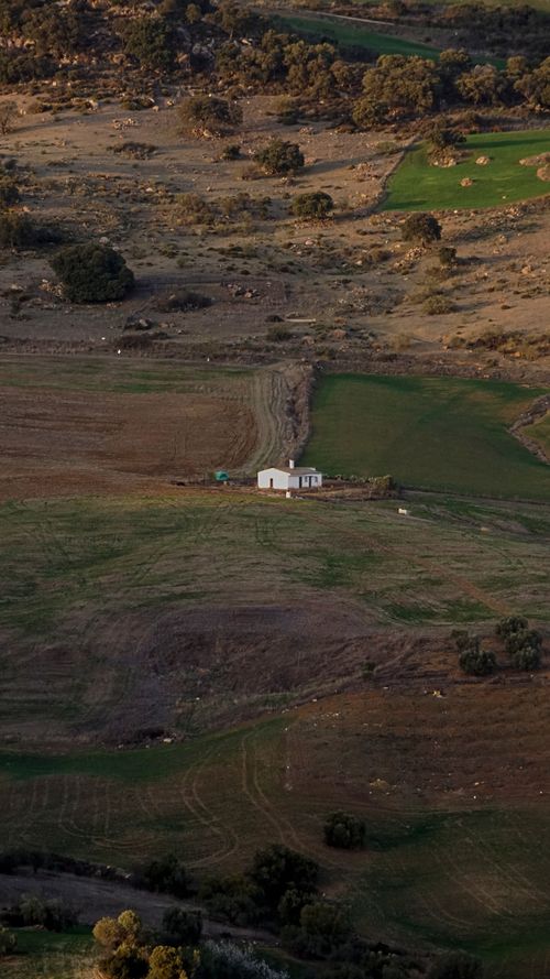 Free Aerial view of a rural farmhouse surrounded by fields and hills, highlighting serene countryside landscape. Stock Photo