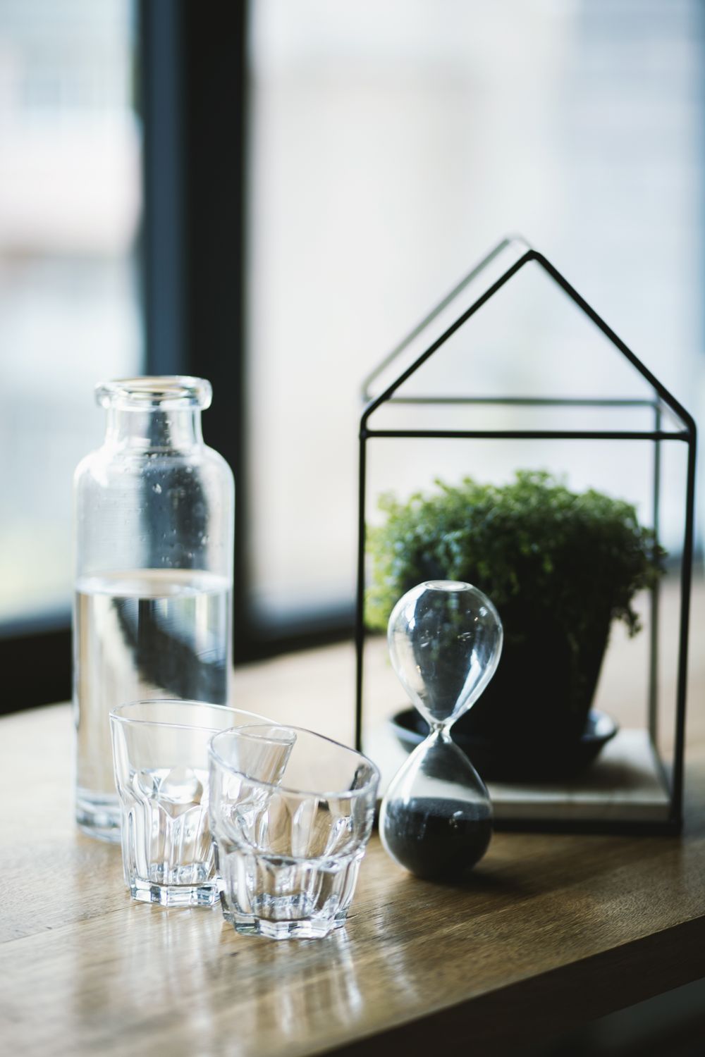 Still life of glassware and an hourglass on a wooden table — photo by EVG Kowalievska on Pexels