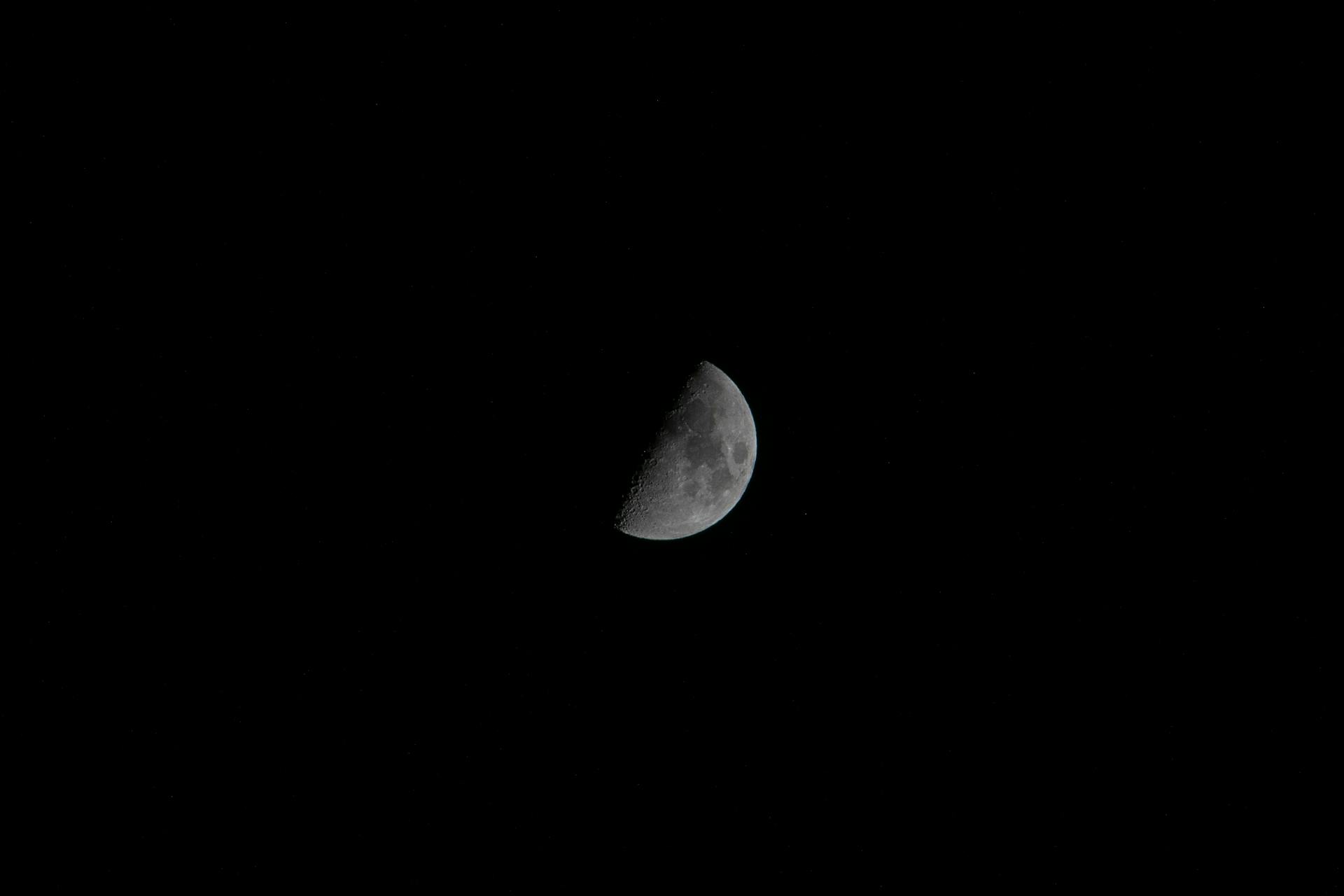 Captivating view of a half moon against a vast dark sky, perfect for celestial themes.