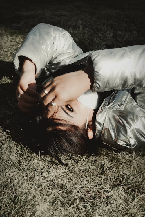 Free A Woman in Gray Jacket Lying on Grass Stock Photo