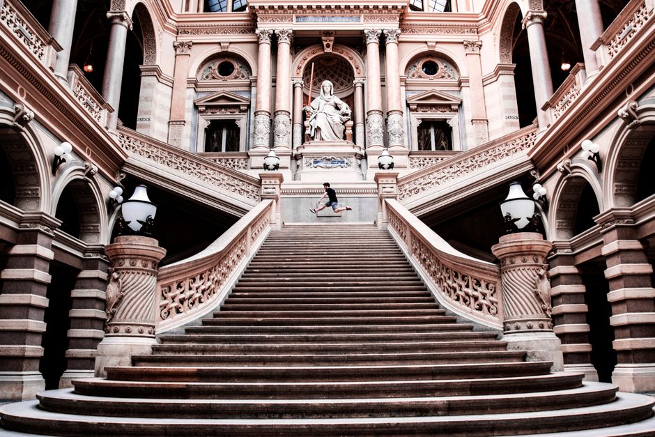 Elegant stone staircase and arches in Austrian landmark with a lone figure.