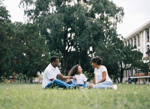 Familie Zittend Op Gras In De Buurt Van Gebouw