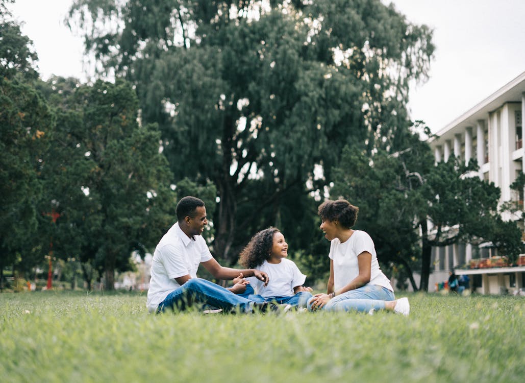 Free Family Sitting on Grass Near Building Stock Photo