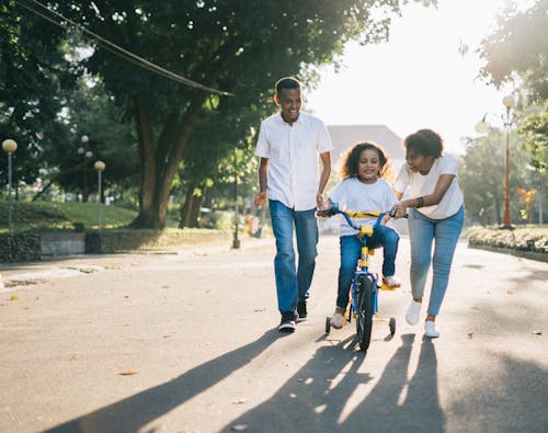站在妻子身边教他们的孩子如何骑自行车的人