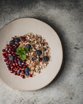 Top-down view of oatmeal with fresh blueberries, pomegranate seeds, and mint leaves.