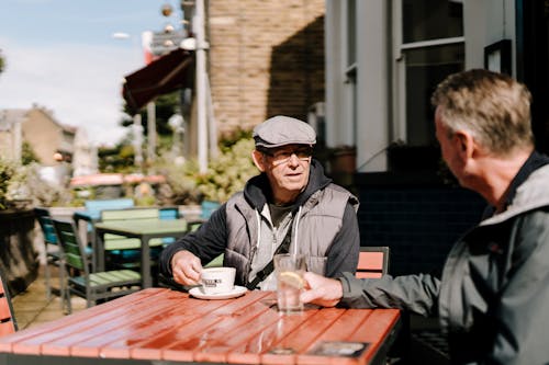 Two Men Sitting in Bar Cafe Patio Talking and Drinking Coffee