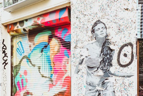 Stencil Art of Woman on Wall Near Door Shutter With Graffiti