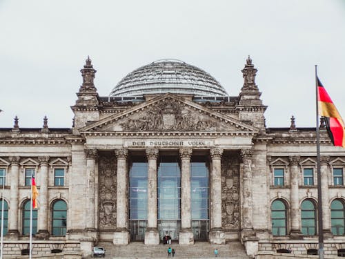 Front view of the historic Reichstag Building in Berlin, Germany, featuring prominent German flags.