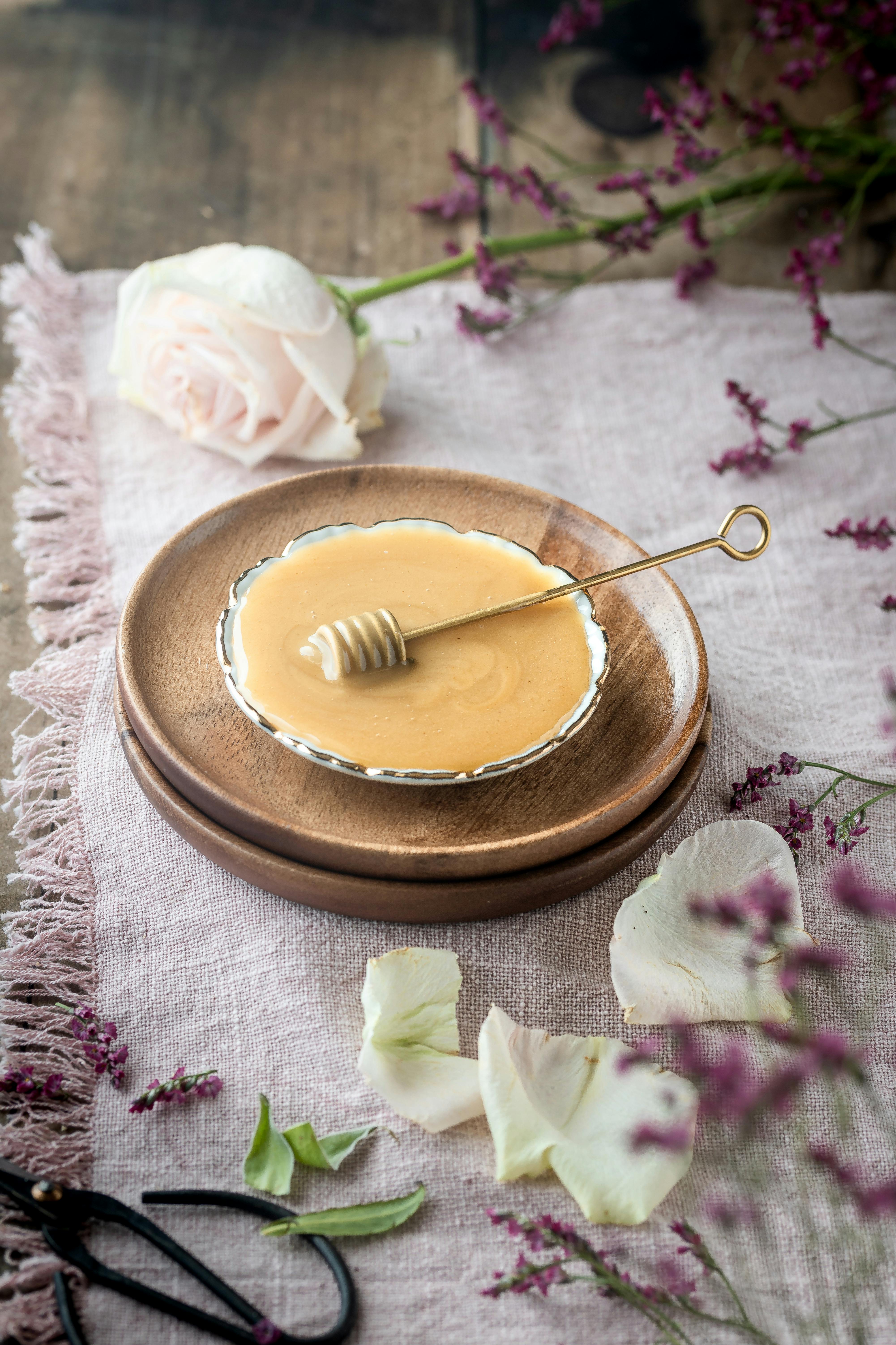 A close-up of honey in a dish with fresh flowers and rustic elements.