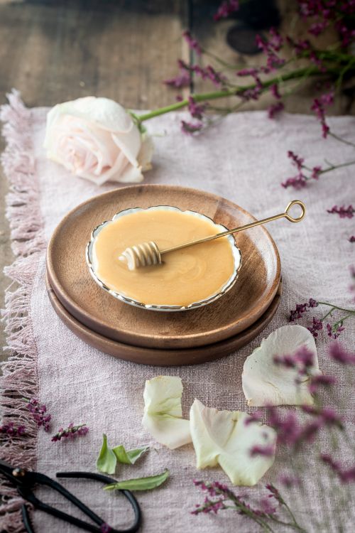 Free A close-up of honey in a dish with fresh flowers and rustic elements. Stock Photo