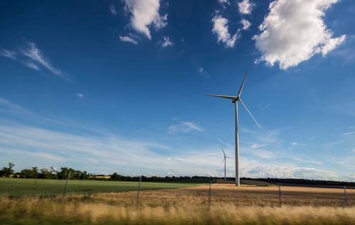 Free Wind turbines generating renewable energy in an open field under a clear blue sky. Stock Photo