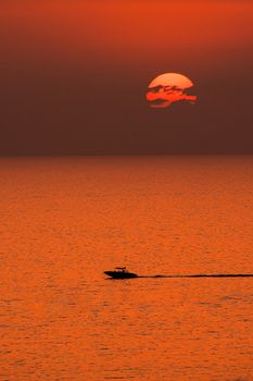 Stunning orange sunset over the sea in Alanya with a silhouette of a speeding boat.