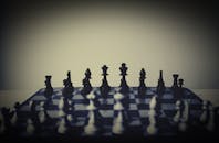 棋盘场景中阴影与突出的棋子成为焦点，整体氛围显得喜怒无常