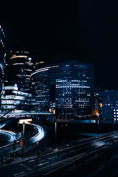 Captivating cityscape at night showcasing modern architecture and light trails from passing vehicles.