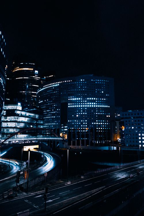 Free Captivating cityscape at night showcasing modern architecture and light trails from passing vehicles. Stock Photo