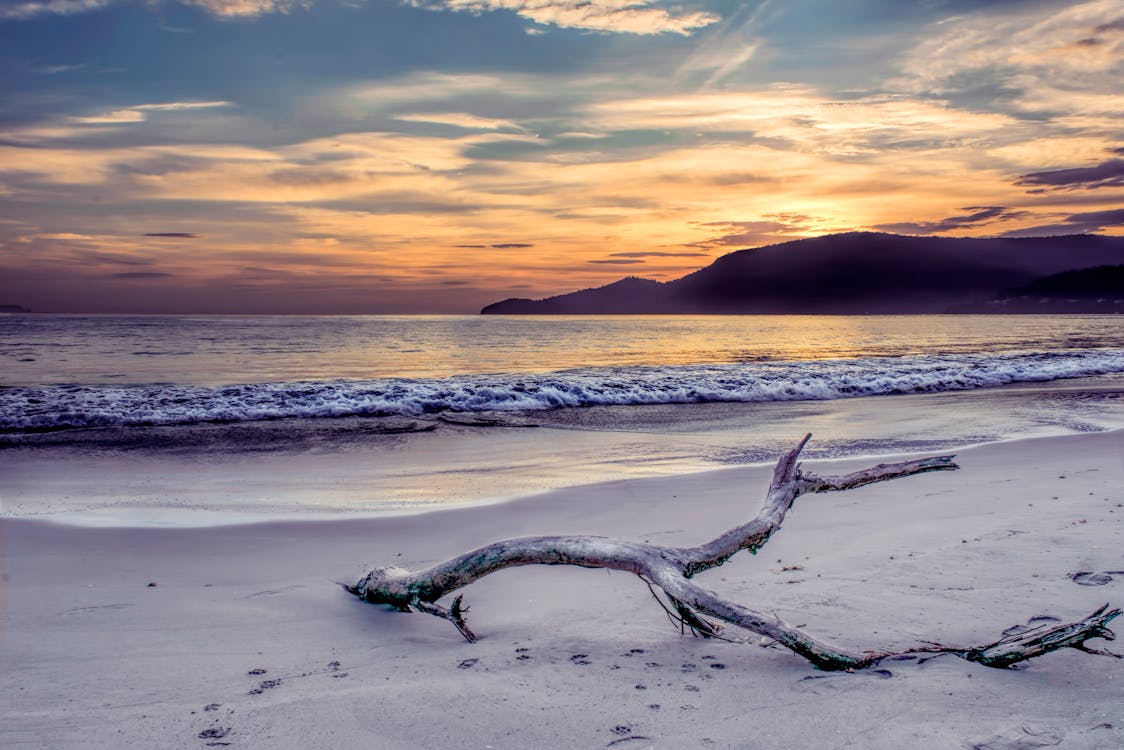 Body of Water Near Mountain Under Gray Sky at Golden Hour