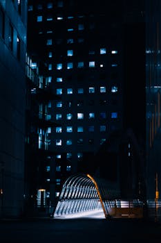 A vibrant city street at night, featuring a lit tunnel and surrounding skyscrapers.