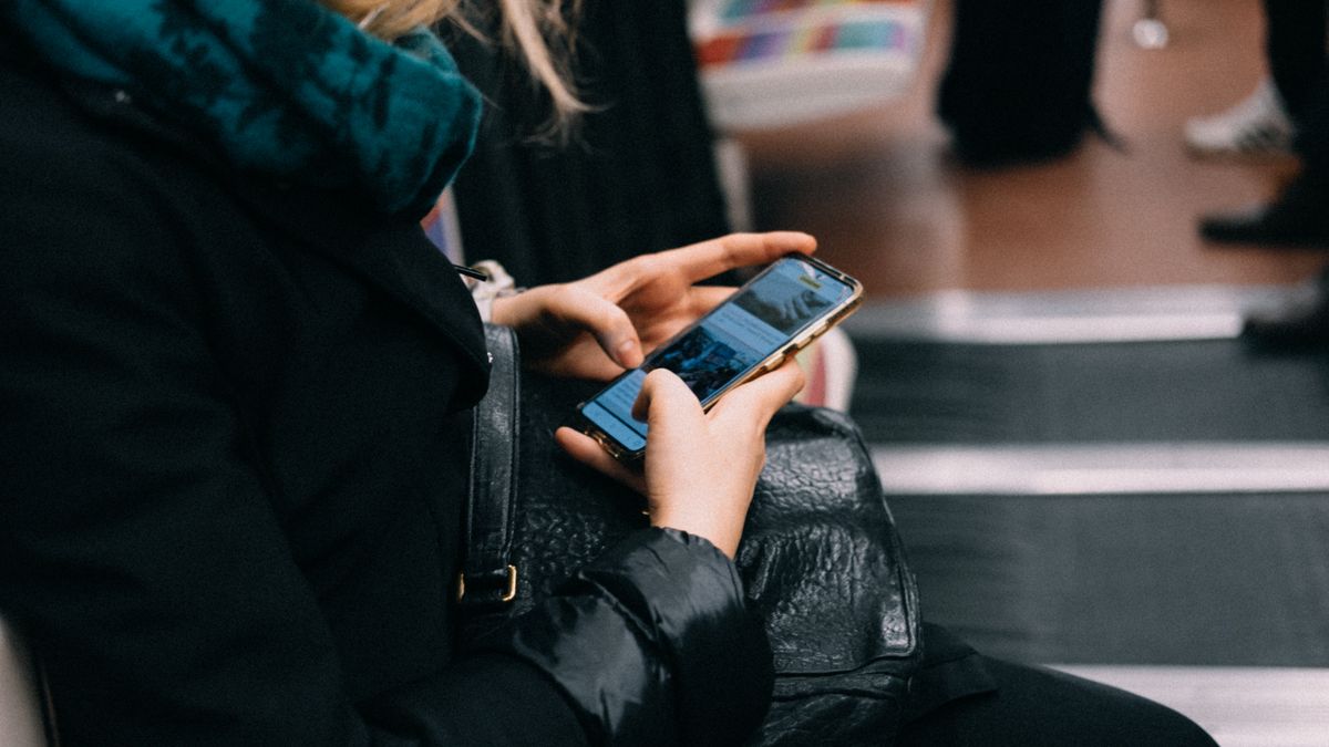 電車で通勤しながらスマートフォンを操作している手元のイメージ