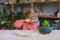 Girl in Red Long Sleeve Shirt Holding Magnifying Glass