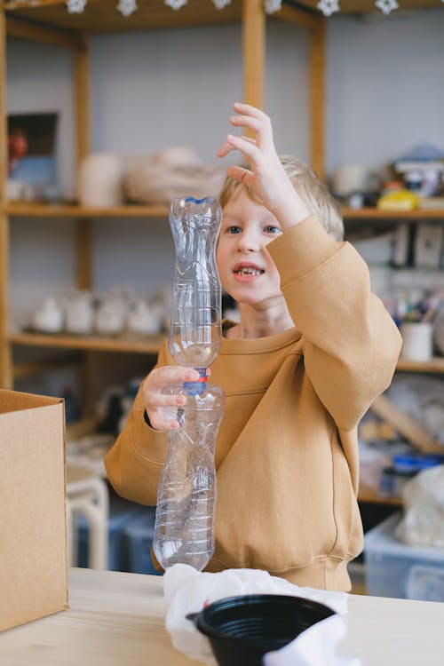 A Boy Playing with Clear Plastic Bottles