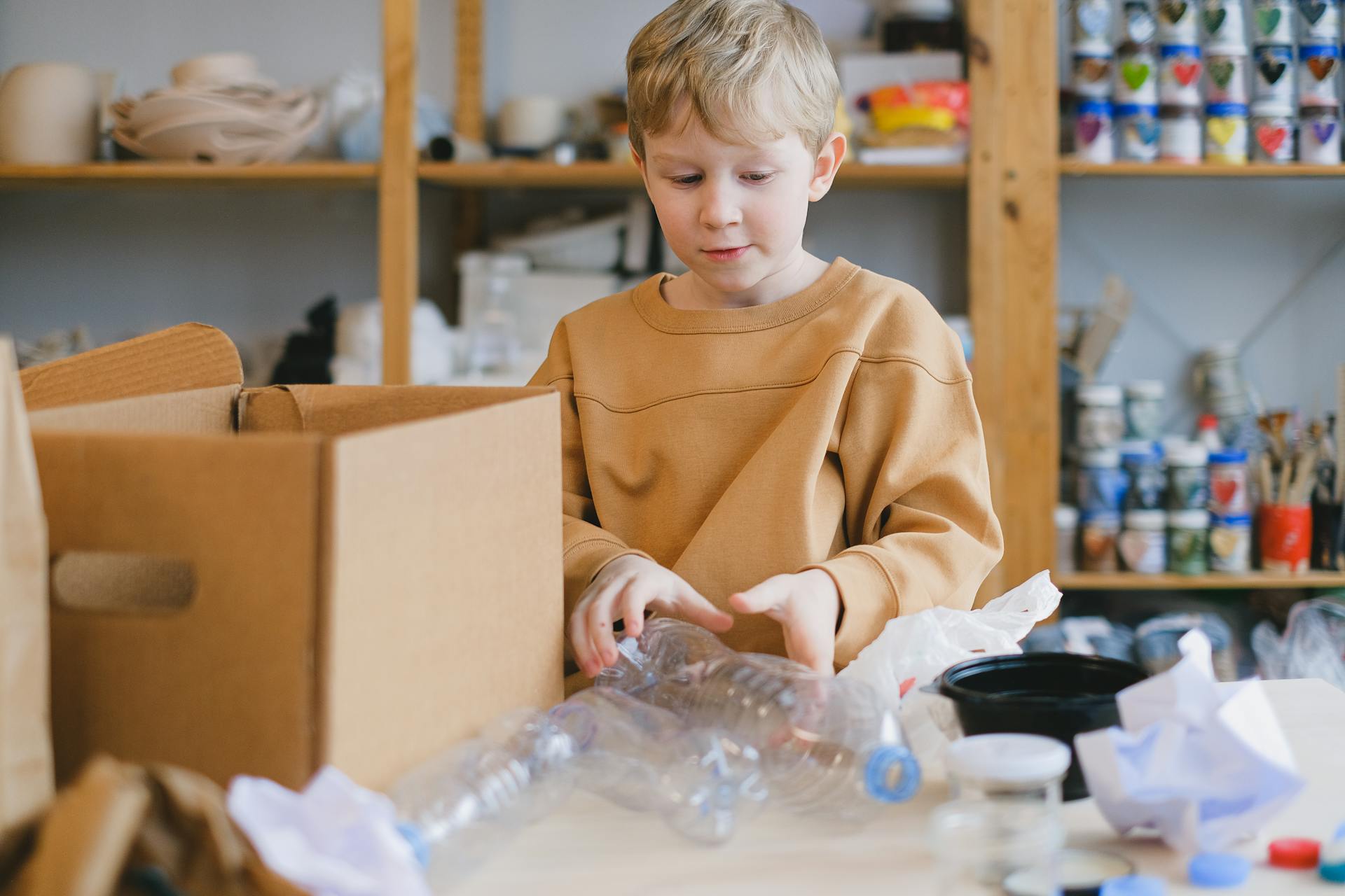 A Boy in Brown Sweater Holding Plastic Bottles