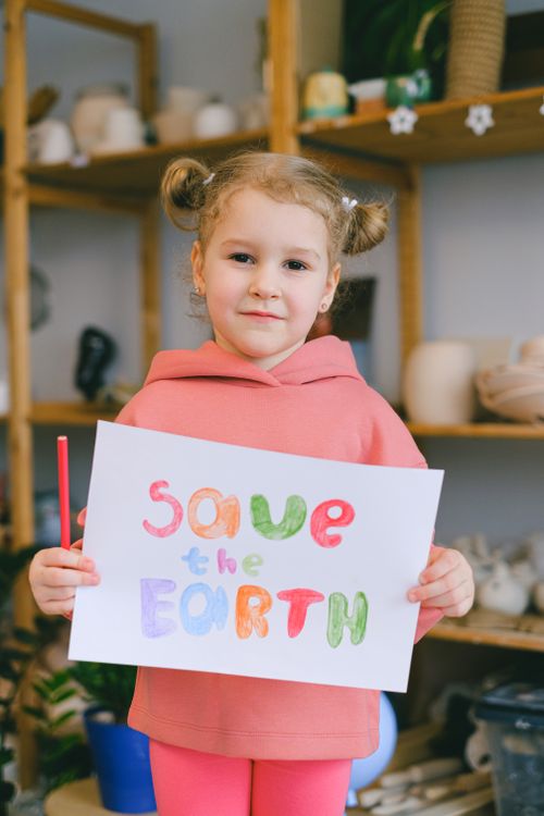 Free Young caucasian girl with a sign advocating for environmental awareness indoors. Stock Photo