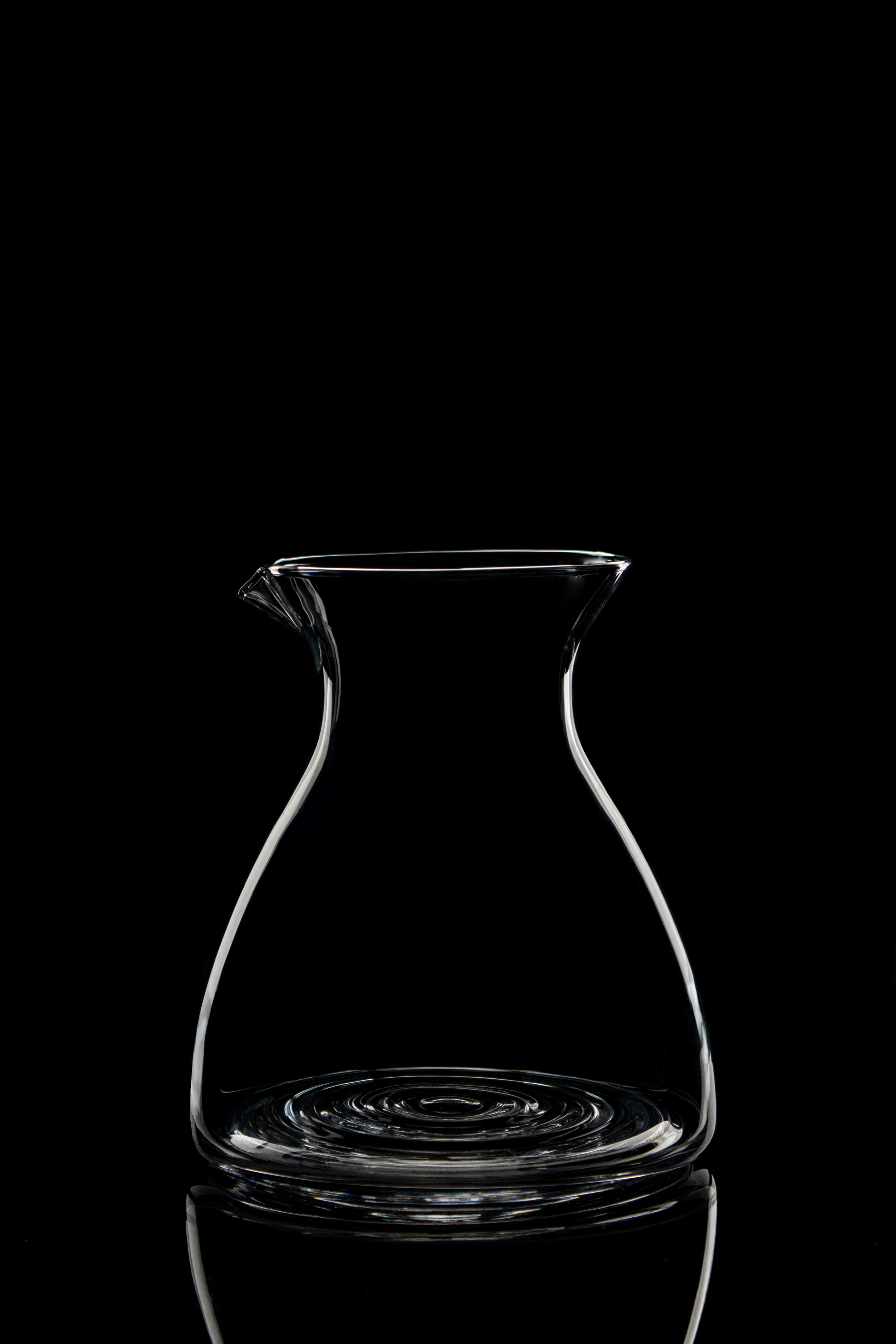 Stylish clear glass decanter on a black background, perfect for minimalistic settings.