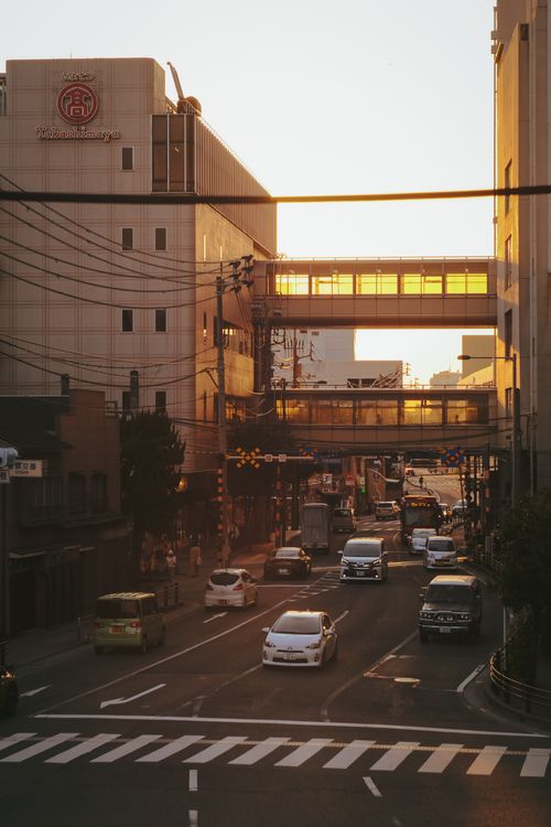Free A bustling city street under a golden sunset, showcasing urban architecture and traffic flow, ideal for cityscape themes. Stock Photo