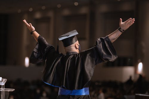 Free Person in Black Jacket and Blue Cap Raising His Hands Stock Photo