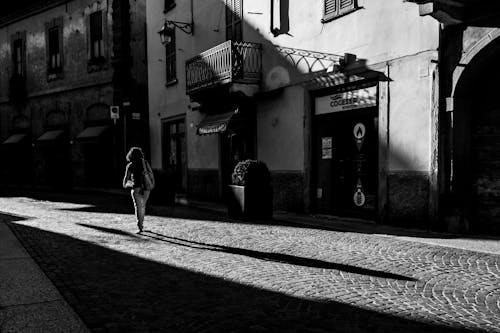 Grayscale Photo of Woman Walking on Sidewalk