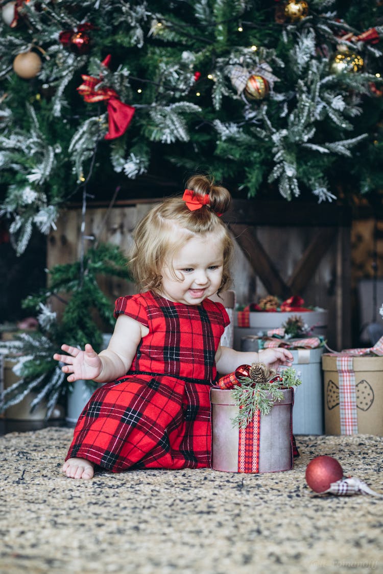 A Baby In Red Dress With A Gift