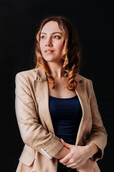 Studio portrait of a woman in a brown blazer against a black background, exuding confidence.