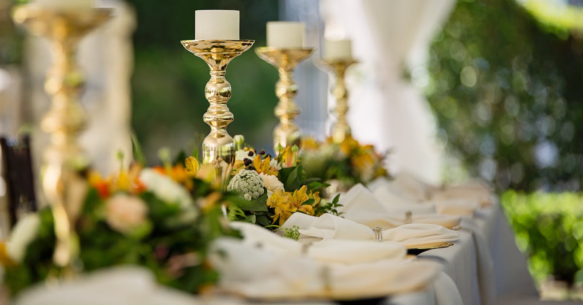 Luxurious outdoor wedding table decor with golden candlesticks and vibrant flower arrangements.