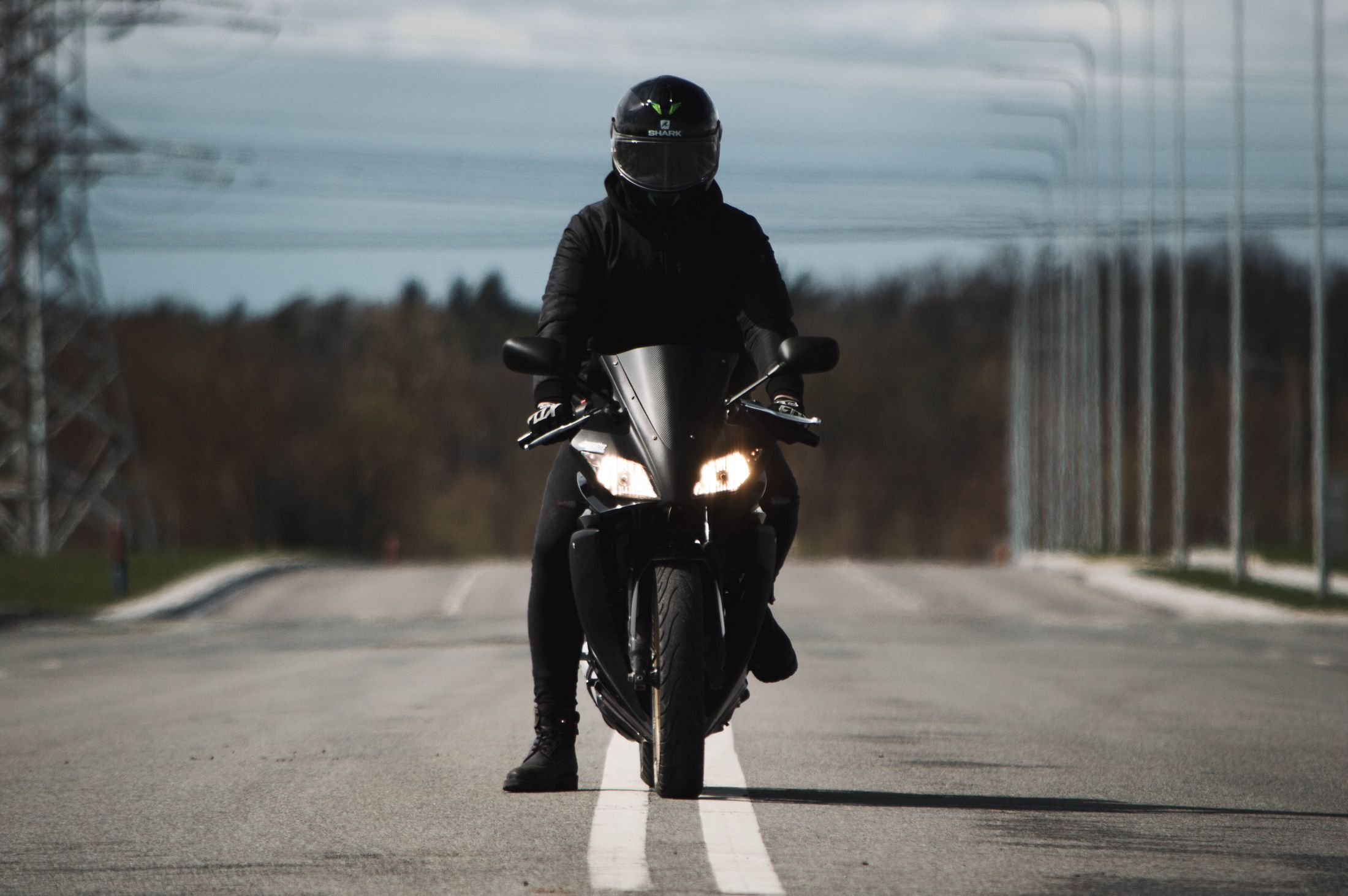 Motorcycle rider wearing all black protective gear on a black sport motorcycle