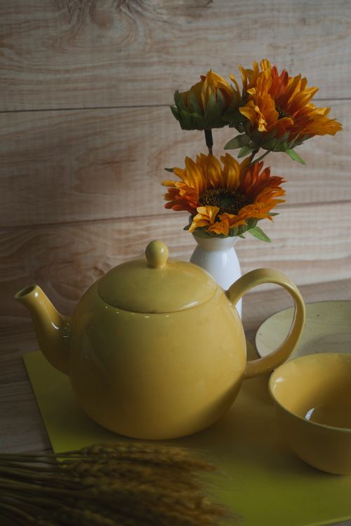 Free Yellow ceramic teapot and sunflowers in a rustic setup. Stock Photo