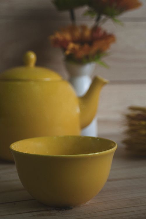 Free Bright yellow ceramic teapot and bowl on a wooden surface, perfect for tea time imagery. Stock Photo