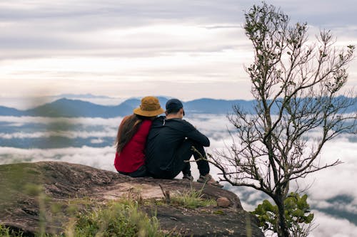 Back View of People Sitting on Mountain Cliff 