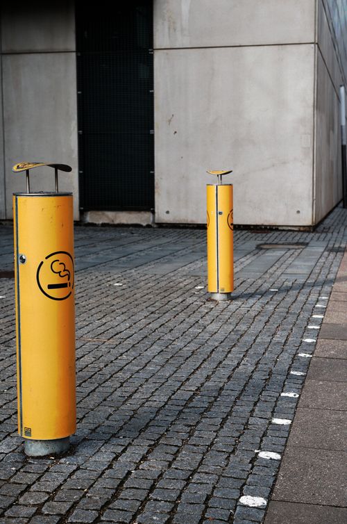 Free Urban environment featuring smoking poles on a paved city street, highlighting urban smoking culture. Stock Photo