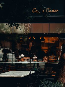 A cozy cafe exterior with a stylish modern facade and glass windows showing the interior seating area.