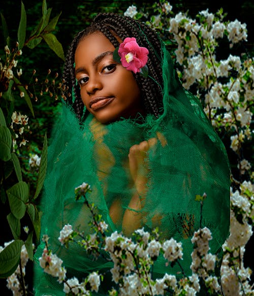 A Girl with Braided Hair Covered with Green Net Surrounded with White Beautiful Flowers while Looking at the Camera