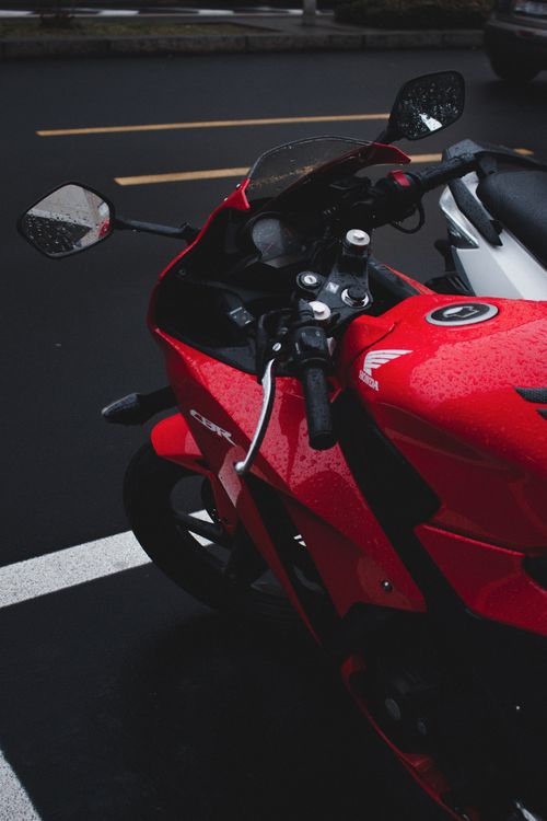 Free Close-up of a red sport motorcycle parked on a wet road outdoors. Stock Photo