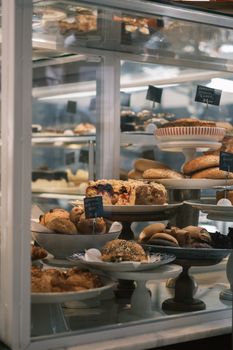 Assorted pastries and baked goods arranged in a charming glass cabinet for a mouthwatering showcase.