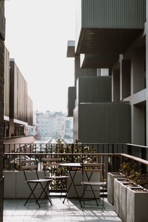 Free A serene city view from a modern balcony with tables and chairs, perfect for relaxation. Stock Photo