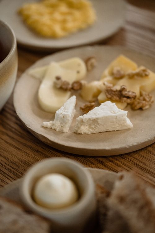 Free Close-up of a cheese platter featuring various cheeses and nuts on a rustic table. Stock Photo