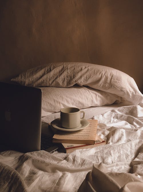 Cup of Coffee, Books and a Laptop on the Bed