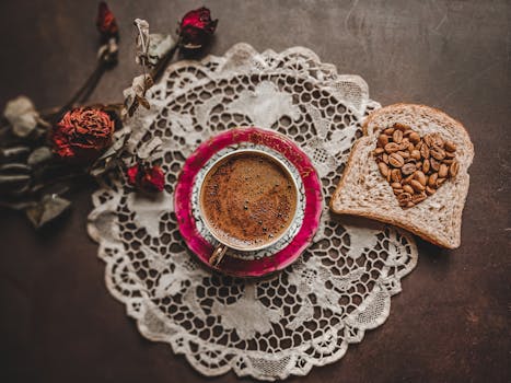 Aesthetic flat lay of Turkish coffee with bread and dried roses on a lace placemat.